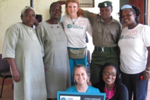 Rosemary Kombo with CCC staff, nurses, and patients pose proudly with International Medical Corps clinic sign.
