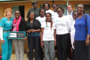 CCC team and Langata Midwives pose happily after graduation with the International Medical Corps dedication sign.